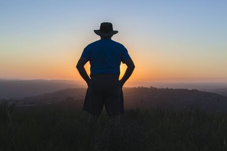 Man rear silhouetted sunset grass hill  landscape.