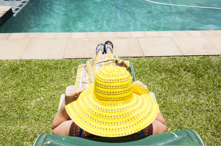 Woman wearing yellow hat relaxing home swimming pool solitude
