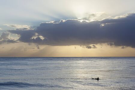 Surfer in ocean waves silhouetted morning sunrise surfing session.