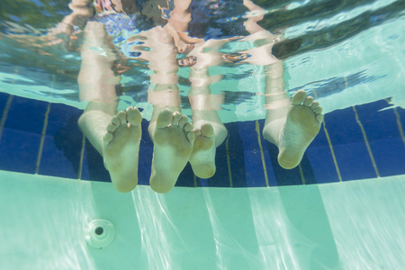 Girl Boy Feet underwater view swimming pool summers dayの写真素材