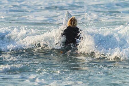 Surfing Surfer paddle out ocean wave white water morning encounterの写真素材