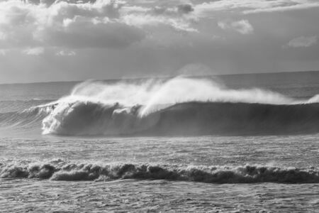 Ocean Waves crashing water power along beach rocky coastline from storm weather.