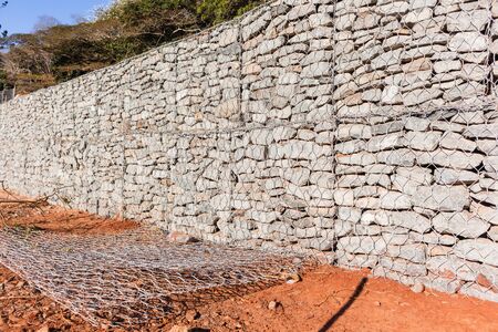 Stone wire cage wall constructed for retaining earth building structures.