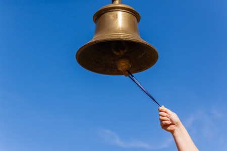 Brass bell with hand closeup ringing sound notice instrument.の写真素材