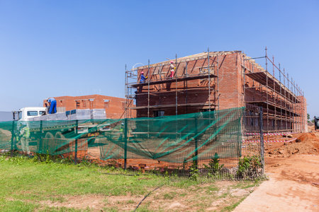 Construction building halfway brickwork wall structures with roof wood frames been installed.のeditorial素材