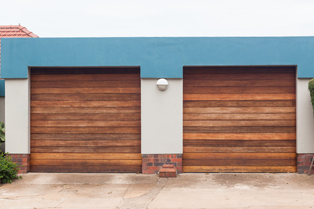 Garage two rollup wood doors for vehicles on roadside entrance.の写真素材