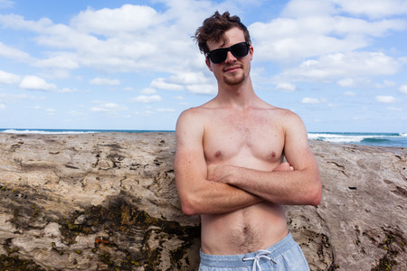 Young man shirtless posing cool casual portrait holidays beach ocean.の写真素材