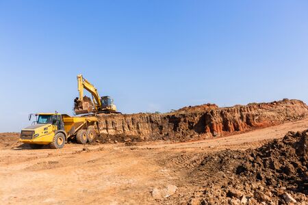 Construction industrial earthworks grader machine loading earth into large truck vehicle