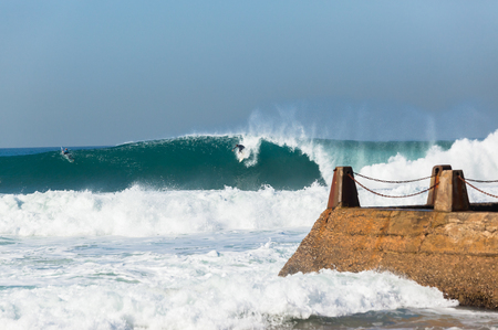 Surfer surfing take off to ride large hollow ocean wave .の写真素材