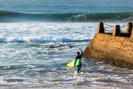 Surfer going surfing enters ocean off  beach reefsの写真素材