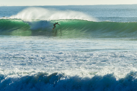 Surfer unidentified surfing catching ocean wave action photoの写真素材