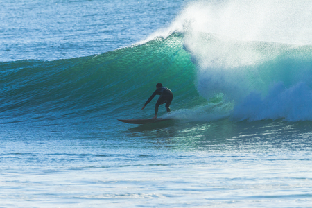 Surfer unidentified surfing catching ocean wave action photoの写真素材