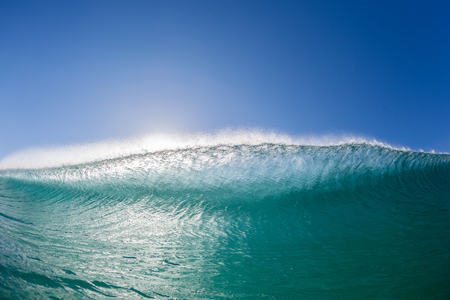 Ocean wave wall surfer swimming view inside hollow crashing blue water closeup face to face confrontation.の写真素材
