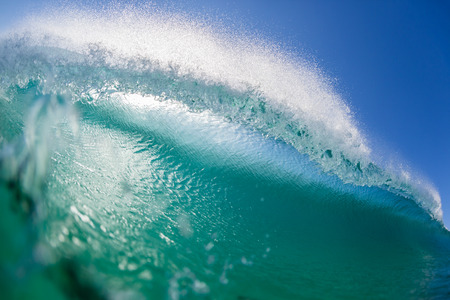 Ocean wave wall surfer swimming view inside hollow crashing blue water closeup face to face confrontation.の写真素材