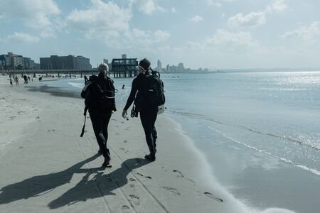 Scuba divers completed ocean reef dives walking  Durban south-beach back homeの写真素材
