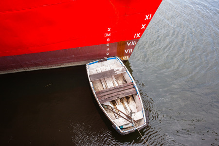 Ship boat with small paddle boat in red paint closeup in hatbor port.
