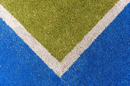 Sports astro synthetic turf field closeup corner boundary white line with green and blue detail.