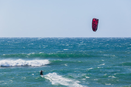 Kite boarder surfer heads out towards ocean horizon through waves.の写真素材