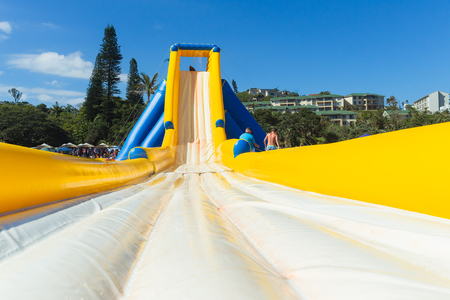 Beach Summer holidays amusment thrill rides down high water slide yellow blue air inflated structure...