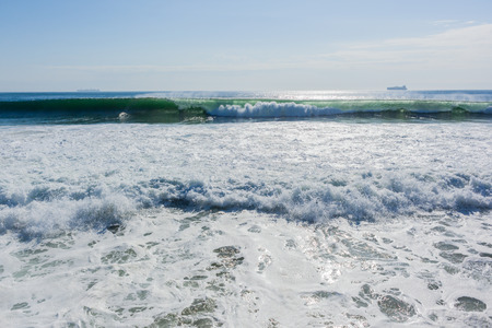 Ocean wave large summer swells with merchant ships on horizon.の写真素材