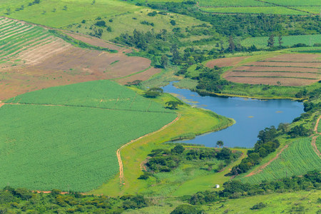 Flying birds-eye view farmlands dam water for crops plowed fields landscape summer green photo.の写真素材