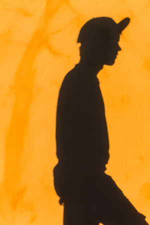 Teenager boy's shadow on yellow textured wall with attitude abstract message.