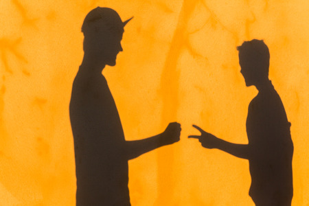 Teenager boy's body rock paper scissors game shadow on yellow textured wall with attitude abstract message.の写真素材