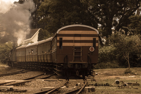 Steam train locomotive closeup exhuasts pulls out of countryside station with smoke exhaust fumes.
