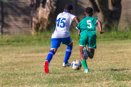 Junior unidentified football soccer teen players on playing field ball action.の写真素材