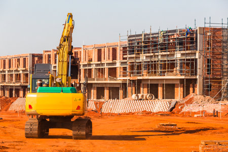 Construction apartments site of new building in progress with earthwork excavator machine.のeditorial素材