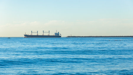 Ship departing out of  harbor port piers onto morning blue ocean seas landscape.のeditorial素材