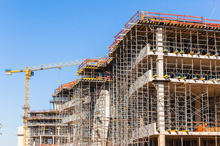 Construction building activity closeup scaffolding floor supports to concrete pouring high building in blue sky.のeditorial素材