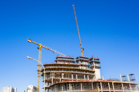 Construction building activity closeup cranes machinery concrete buckets pouring high building in...