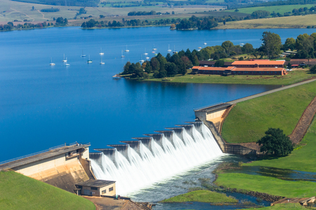 Flying air photo of dam wall overflowing waters moored boats scenic countryside landscape.の写真素材