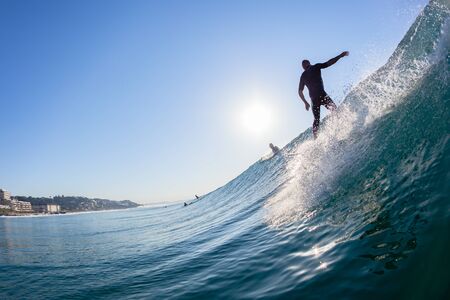 Surfing Surfer silhouetted rear behind water swimming photo ocean wave ride into the morning sun  at...