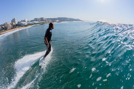 Surfing Surfer rear behind perspective water photo ocean wave ride into the morning sun at Ballito Bay beach..の写真素材