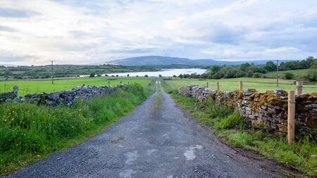 Rural road route farm countryside  scenic panoramic perspective toward lough lake landscape in North West Ireland.の写真素材