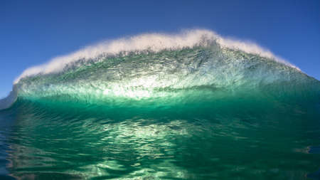 Ocean wave swimming encounter face to face closeup of curling pitching crashing  lip of sea water towards camera with panoramic  sun backlighting.の写真素材