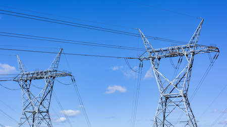 Electricity power lines two steel tower structures in blue sky closeup panoramic photo.