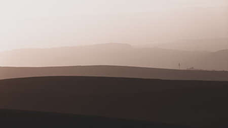 Countryside farmlands hills scenic morning dawn light sky sepia cross colors contrasts over the panoramic landscapeの写真素材