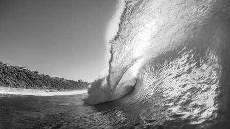 Ocean wave hollow crashing sea water onto shallow reef with backlight sun close-up swimming in...