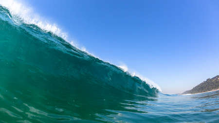 Ocean wave swimming close up confrontation perspective of long wall of sea water and clear sky.の写真素材