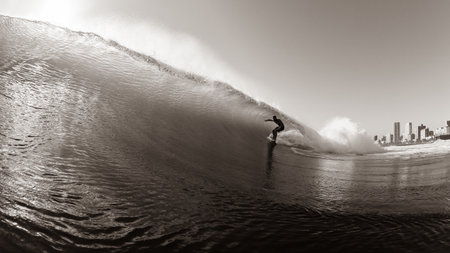 Surfer Silhouetted Surfing ocean wave water action sepia photographの写真素材