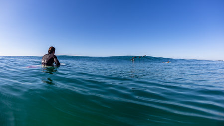 Surfers surfing unrecognizable rear water photograph sitting on surfingboards waiting for ocean wavesの写真素材