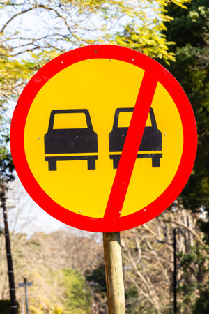 Road sign on pole with one vehicle instruction route illustration in black yellow and red paint.の写真素材