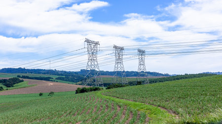 Electricity steel tower pylons with suspended cables stretching over countryside farmlands transporting electrical power energy for the economy .の写真素材