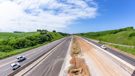Driving road highway through construction expansion improvements with barriers, earthworks, new lanes for vehicle traffic flow.の写真素材