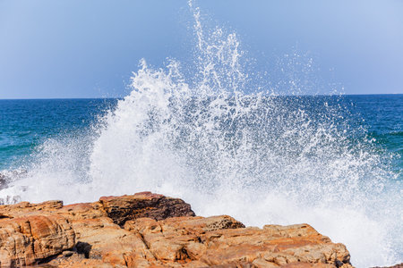 Rocky beach coastline with ocean blue waves crashing white sea white water horizon landscape.の写真素材