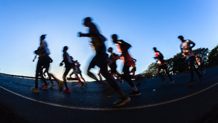 Marathon runners motion speed blurs silhouetted morning dawn sunrise running up hill in ultra...