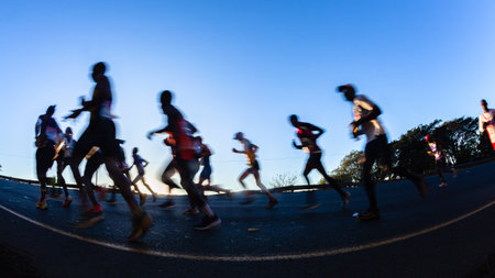 Marathon runners motion speed blurs silhouetted morning dawn sunrise running up hill in ultra distance raceの写真素材